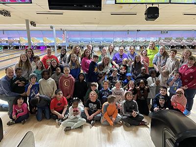 group photo of students and staff with bowling lanes behind them